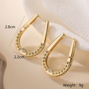 Gold plated horseshoe earrings with small beads and zircon stones on a beige fabric base