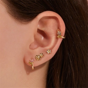 Primer plano de pendientes florales y broches con cristales chapados en oro de 18K