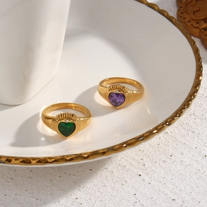 Detail of 18K gold-plated heart rings with green and purple zircon on ceramic plate