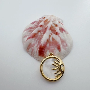 Detail of 18K gold plated sun and face pendant featuring natural white shell inlay