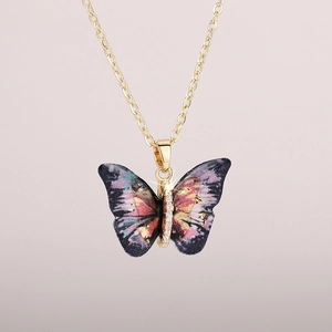 Detailed close-up of acrylic butterfly pendant with gold foil and zircon embellishments