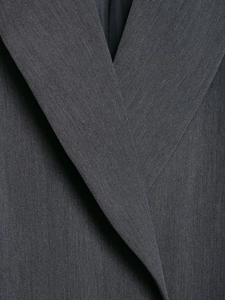 Détail du revers d'un blazer gris foncé montrant la texture du tissu de haute qualité