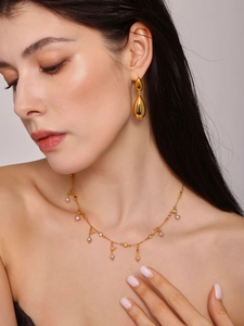 Close-up of golden bird and pearl necklace set with elegant waterdrop earrings on model