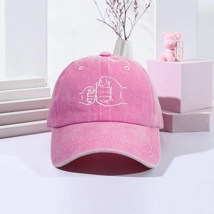 Close-up of vintage washed pink baseball cap featuring a white fist bump embroidery
