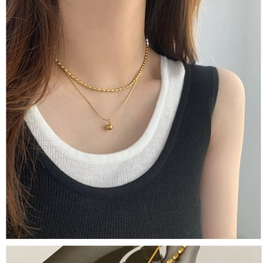 Close-up of 18K gold-plated double-layer necklace with beads and small gold ball pendant