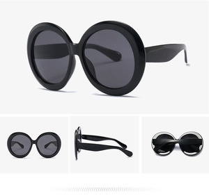Detail view of black oversized round sunglasses with glossy frames and dark lenses