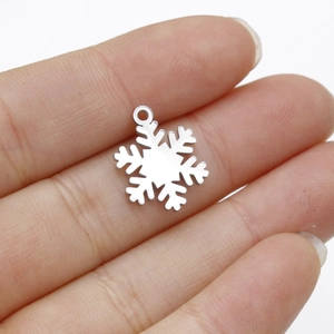 Polished silver snowflake pendant on a finger showing realistic 15.5x12mm size detail