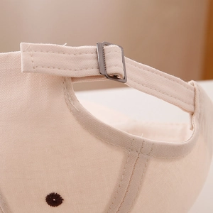 Détail de la boucle en métal et des coutures sur la casquette en coton beige enfant