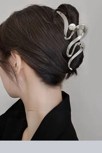 Silver wavy metal hair claw with pearl accent worn on a professional bun hairstyle