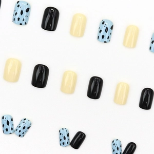 Short square press-on nails in cream, black, and blue cow print with glossy finish