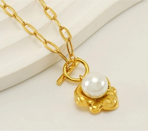 Macro detail of paperclip chain necklace with pearl pendant and golden toggle clasp