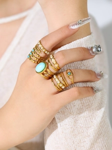 Detail of stacked gold stainless steel rings with turquoise and turquoise eye stones