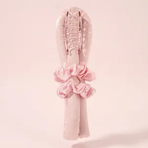 Close-up of pink satin heatless hair curler set with matching scrunchies and large hair claw