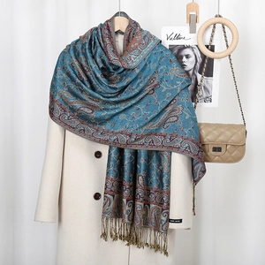 Close-up of blue paisley scarf with red fringes and handmade label on an elegant coat