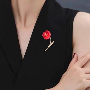 Detail of red floral brooch with zircon accents worn on a black V-neck top