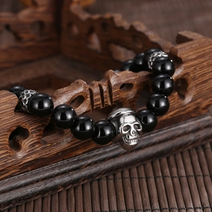 Detailed close-up of tiger eye skull bracelet on vintage wooden display stand