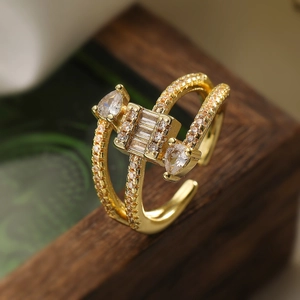 Gold plated geometric open ring with cubic zirconia stones on walnut wood surface