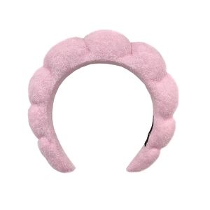 Pink puffy spa headband made of soft towel fabric on a clean white background