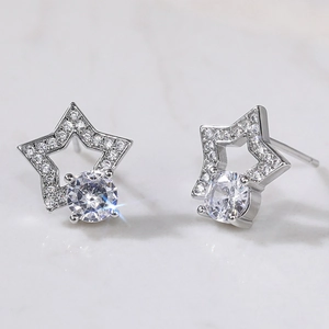 Detailed close-up of silver star stud earrings with round cubic zirconia on marble