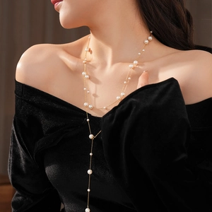 Macro shot of tiered gold chain pearl necklace on model for elegant styling