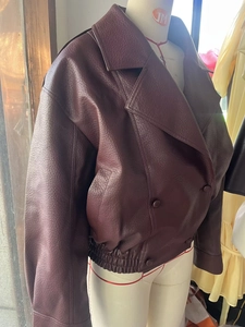 Detail of burgundy oversized faux leather jacket featuring wide lapels and elastic hem