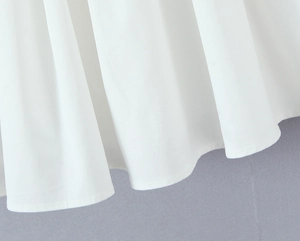 Close-up of white French embroidered dress hem showing detailed stitching and fabric texture