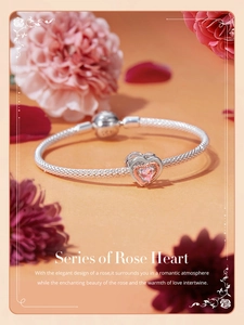 Detailed view of silver heart charm with pink gemstone and rose gold accents on a bracelet