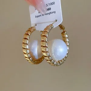 Elegant gold plated round crumpled hoop earrings featuring a large white pearl center