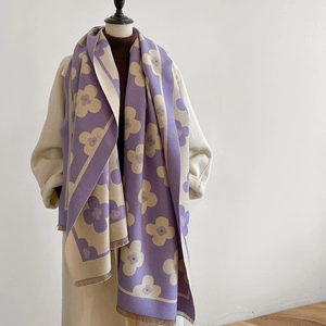Close-up of floral thick knit scarf with fringe edge on a mannequin with white coat