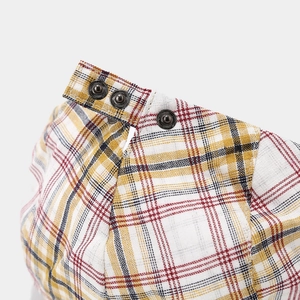 Macro view of adjustable metal buttons and plaid fabric texture on the newsboy cap