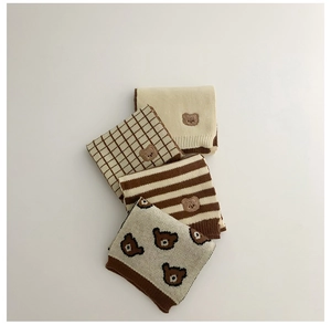 Detail of four knit kids scarves in cream and brown with cute bear embroidery patterns