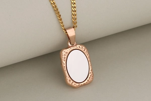 Macro detail of rectangle rose gold pendant with hammered edges and white inlay