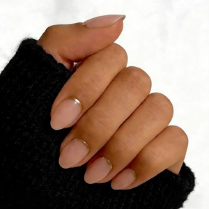 Close-up of nude pink short square press-on nails with thin gold metallic line accents