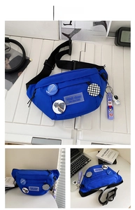 Detail of blue sports chest bag with badges and cute astronaut keychain accessory