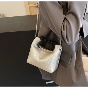 Detail of silver textured leather mini bag with black spherical handle and chain strap