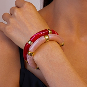 Gros plan d'un bracelet géométrique en acrylique avec détails dorés au poignet
