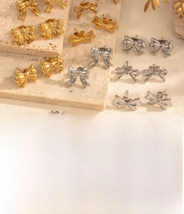 Detailed view of titanium steel bow earrings in gold and silver with elegant finish