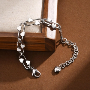 Polished stainless steel paperclip chain bracelet with heart pendants on a wooden frame