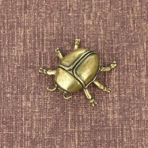Primer plano del adorno de mariquita de latón vintage con textura de metal detallada