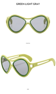 Detail view of oversized futuristic green sunglasses with hollowed-out temples and gray lenses