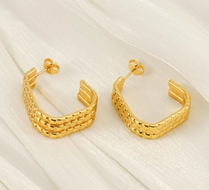 Detailed close-up of gold U-shaped earrings with three-layer woven texture on silk