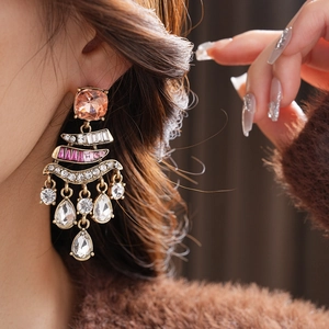 Detail of vintage gold earrings with pink and purple crystal tassels worn by a model