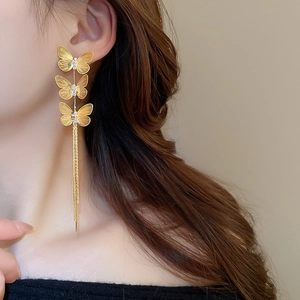 Close-up of gold butterfly tassel earrings on model showing elegant dangling design details