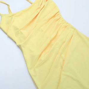 Detailed view of side ruched texture and elastic fabric on a light yellow maxi dress