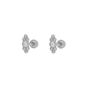 Detailed macro view of silver stud earrings with clear zircon and beaded texture