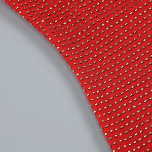 Macro detail of red knitted dress fabric with densely set gold rhinestones