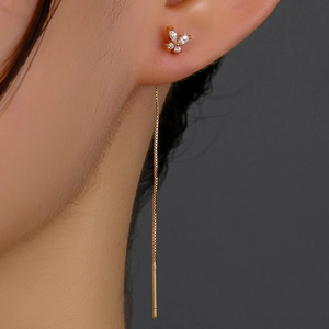 Close-up of golden butterfly tassel earrings with sparkling cubic zirconia on a model