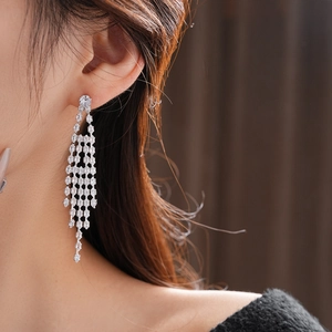 Close-up of silver tassel earrings with sparkling cubic zirconia on model ear