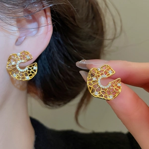 Detailed macro view of gold-plated hollow C-shaped earrings with inlaid zircon crystals