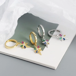 Detailed close-up of S925 silver star earrings with colorful zircon stones on white fabric